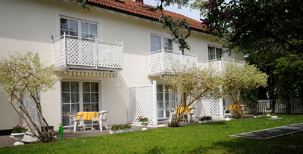 Aussenansicht Gebäude mit Balkonen, Terassen und freundlicher Bepflanzung im Grünen.