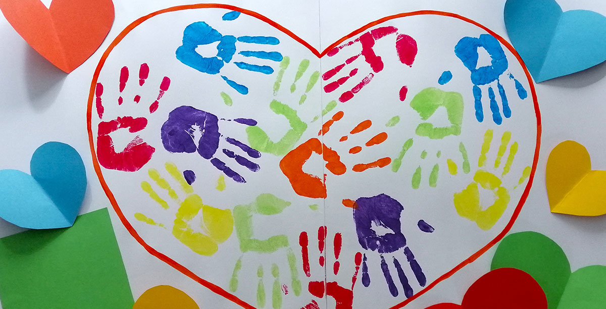 Bastelarbeiten in Form eines Herzens, gefüllt mit bunten Handabdrücken