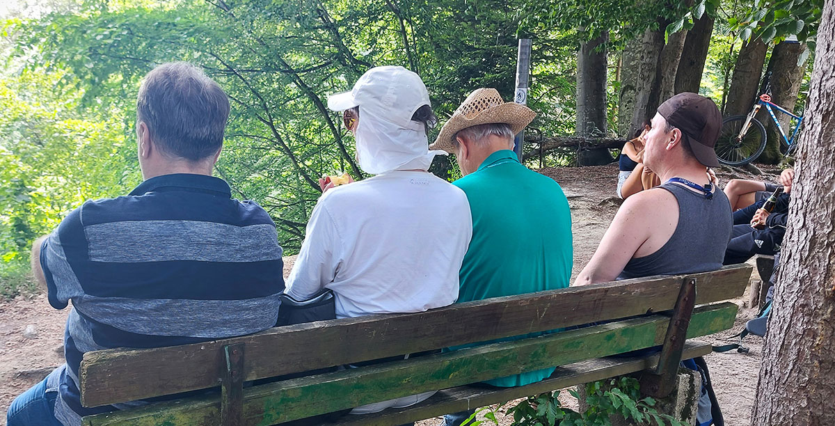 Bewohner rasten beim Ausflug auf einer Bank, mit Blick auf den Wald